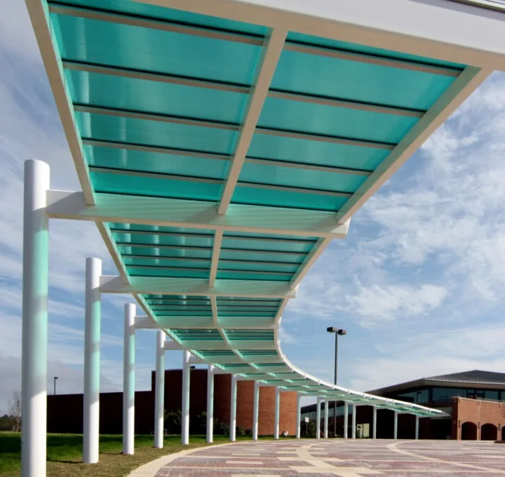 Translucent canopy with teal polycarbonate glazing sheltering a curved campus walkway